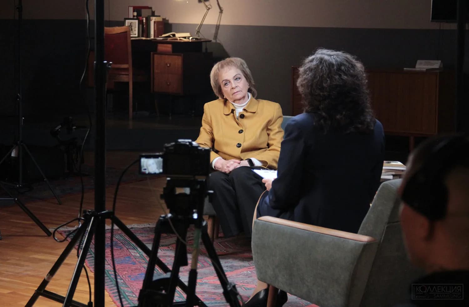 Интервью на площадке: герой и интервьюер, камера на штативе и световое оборудование в кадре